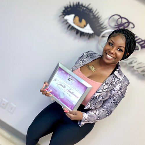 Artist holding her certificate of completion after brow training in Houston
